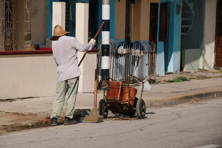 A man is cleaning an indoor glass door with a spray bottle and cloth.